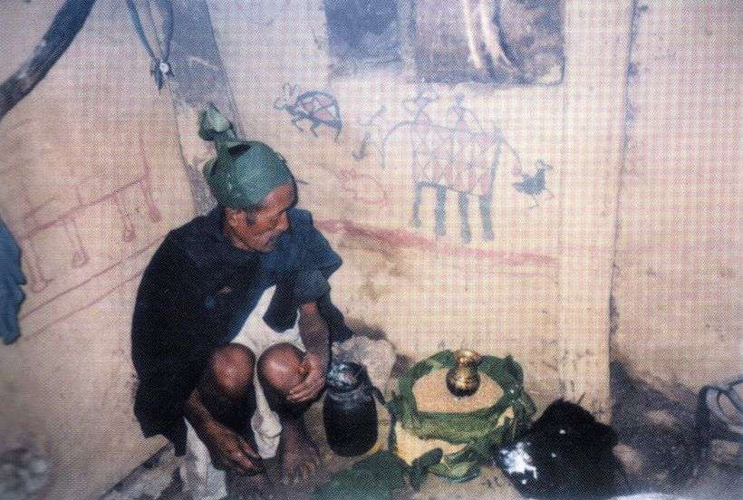 Magar sámán a házában; tõle jobbra az áldozati bika levágott feje, a falakon saját festményei láthatóak